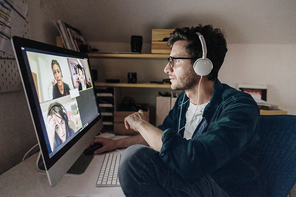 A man sitting in front of his desktop, having a team video call meeting.
